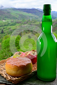 Natural Asturian cider made fromÂ fermented apples and Asturian cow cheese and view Picos de Europa mountains on background